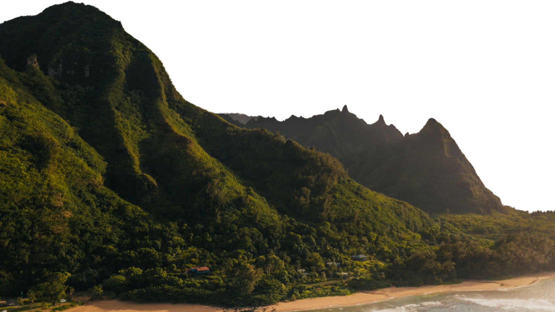 Green mountains rising from a beach in Hawaiʻi